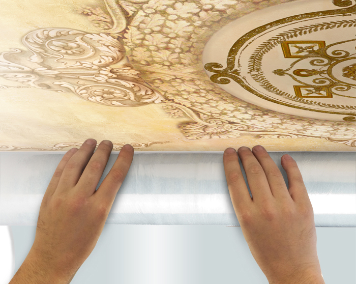5.Отмотайте примерно 50 см полотна фрески, снимая пленку, и приложите к потолку. Тубус с фреской держите как можно ближе к потолку.